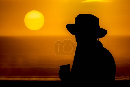 Silhouette de personne savourant le coucher du soleil au bord de la mer