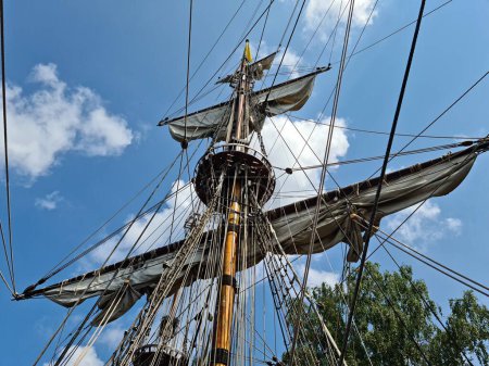 Téléchargez les photos : Sails collected on the yards of an old wooden sailing ship after arriving at the port. - en image libre de droit