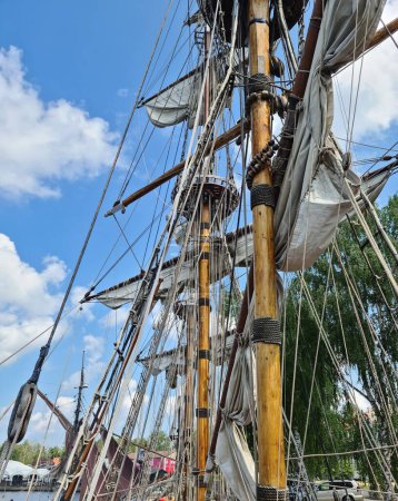 Téléchargez les photos : Sails collected on the yards of an old wooden sailing ship after arriving at the port. - en image libre de droit