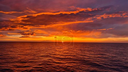 Foto de Los rayos del sol de la puesta de sol pintaron las nubes y el mar con colores escarlata. - Imagen libre de derechos