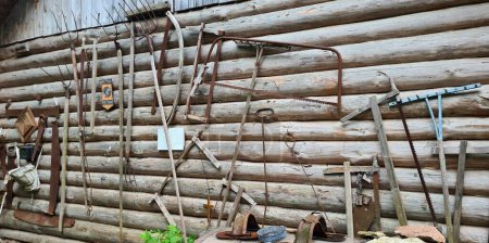 Collection of old agricultural tools gathered on the wooden wall of the barn.