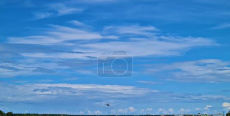 Plane gains altitude after takeoff against the background of blue cloudy sky.