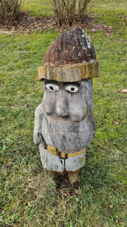 Small figure of gnome made of wood on green grass in early spring.