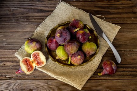 Téléchargez les photos : Figues mûres, grandes et douces dans une assiette et un couteau sur une table en bois close-up - en image libre de droit