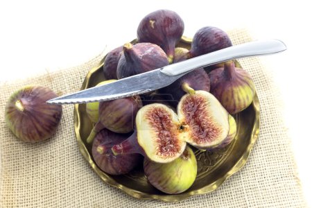 Photo for Ripe, big, sweet figs in a plate and a knife on a white background close-up - Royalty Free Image