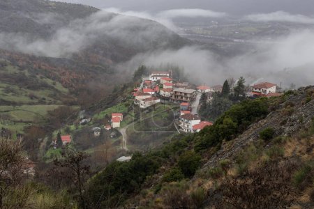 Schöne Aussicht auf Berge, Nebel und Dorf (Griechenland, Epirus) an einem bewölkten, kalten und winterlichen Tag