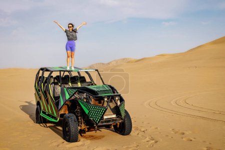 Foto de La chica está parada encima de un buggy de coche. Un SUV en el desierto. - Imagen libre de derechos