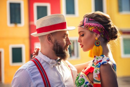 A beautiful young couple - a man and a woman against the background of colored houses. Burano Island. Italy