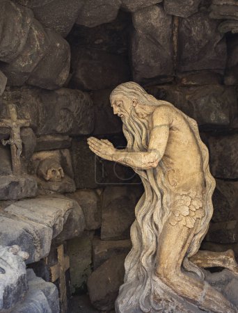 An old hermit prays in a cave. A stone statue of a hermit monk near St. George's Cathedral , Lviv, Ukraine