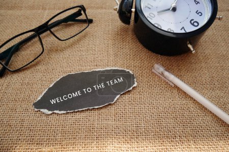 Photo for WELCOME TO THE TEAM written on torn black paper with waker clock, glasses, pen and burlap - Royalty Free Image