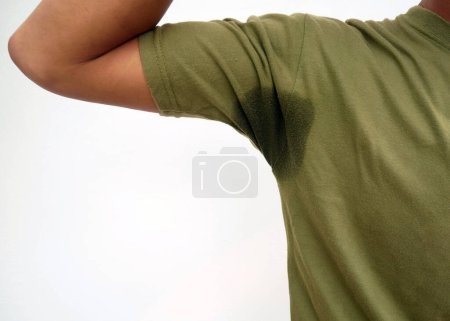 Photo for Hyperhidrosis sweating. Young Asian man with sweat stain on his clothes with white background. Health care concept. - Royalty Free Image