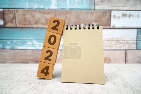 Foto de Papel portátil en blanco con 2024 cubos sobre fondo de pared de ladrillo. 2022 maqueta de año nuevo, plantilla con espacio de copia para el texto - Imagen libre de derechos