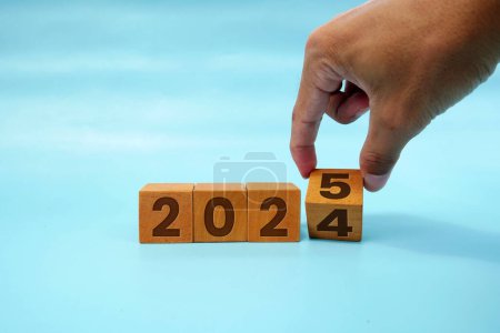 Hand flipping block 2024 to 2025 text on table. Resolution, time, plan, goal, motivation, reboot, countdown and New Year holiday concepts