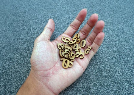 Stack of wooden numbers in man's hand.
