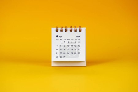 April 2024 desk calendar on yellow background with copy space.