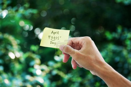 Hand holding a stick note with April Fools Day text