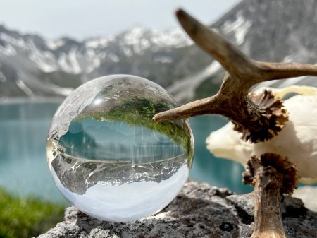 Foto de Astas Roebuck junto a Lensball, bola de cristal, con reflejos del lago Lunersee (Lnersee, Montafon, Vorarlberg). En el fondo, las famosas montañas Rtikon, una de las regiones de alta montaña más impresionantes de Austria y los Alpes europeos. - Imagen libre de derechos