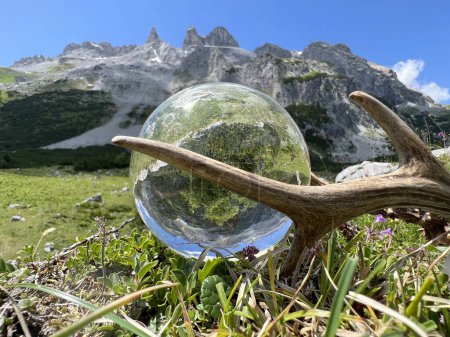 Foto de Impresionantes cuernos de roebuck (trofeo de caza), junto a lente, bola de cristal, reflejos del valle Gauertal (Drei Tuerme, Sulzfluh, Montafon, Vorarlberg). Una de las regiones alpinas de alta montaña más famosas de Austria y los Alpes europeos. - Imagen libre de derechos