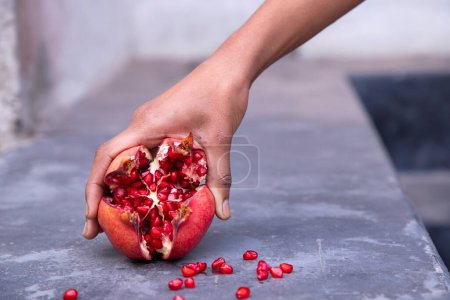 Téléchargez les photos : Ripe pomegranate fruit in woman hand on concrete background - en image libre de droit