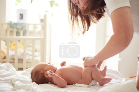 Foto de Mother Massaging Her newborn baby boy. Realistic home portrait - Imagen libre de derechos