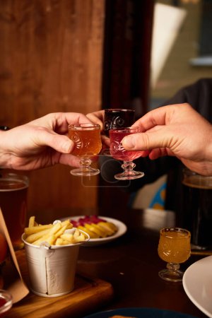 Téléchargez les photos : Homme et femme boivent différentes liqueurs au pub. Amis prenant des boissons alcoolisées au bar - en image libre de droit