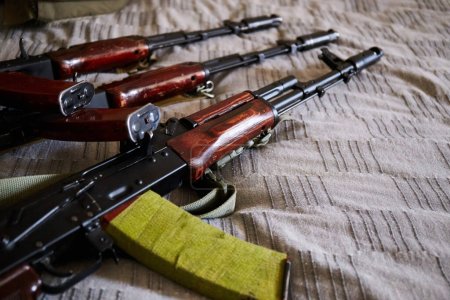 Téléchargez les photos : Kalashnikov assault rifle on bed. Ukrainian home. Russia's military aggression against Ukraine - en image libre de droit