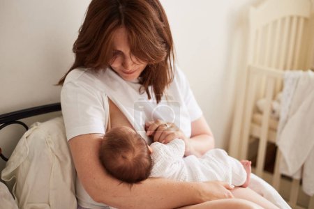 Foto de Mother breastfeeding her newborn baby boy. Realistic home portrait - Imagen libre de derechos