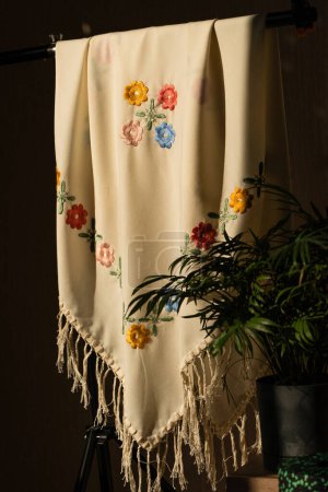 close-up image of white fabric with intricate embroidery featuring colorful flowers and leaves.