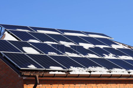 Panneaux solaires recouverts de neige, sur le toit du chalet. Énergie verte pour le chauffage en hiver.