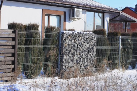 Téléchargez les photos : La clôture de la maison est faite de sections successives de gabion, planches de bois et thuja. - en image libre de droit
