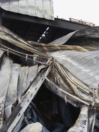 Foto de The roof of the warehouse building that was deformed and collapsed due to the fire - Imagen libre de derechos