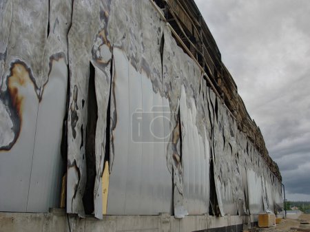 Foto de Consecuencias de un incendio en un almacén, paredes semidestruidas carbonizadas hechas de paneles sándwich. - Imagen libre de derechos