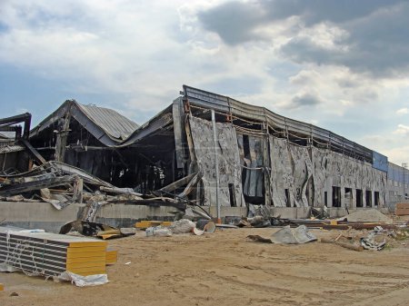 Foto de Consecuencias de un incendio de almacén, donde las paredes hechas de paneles sándwich están parcialmente carbonizadas y medio destruidas. - Imagen libre de derechos