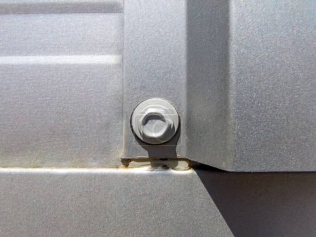 Close-up of shiny grey metal facade fastened by silver screw.