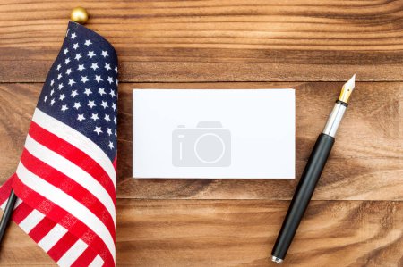 Foto de Tarjeta de visita en blanco con bolígrafo y bandera americana sobre la mesa. Vista superior. - Imagen libre de derechos