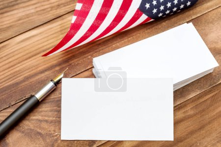 Foto de Tarjeta de visita en blanco con bolígrafo y bandera americana sobre la mesa. - Imagen libre de derechos