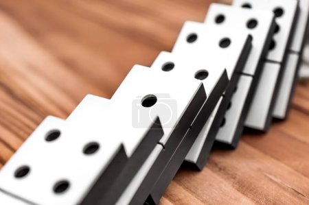 Row of falling dominoes on the wooden table.
