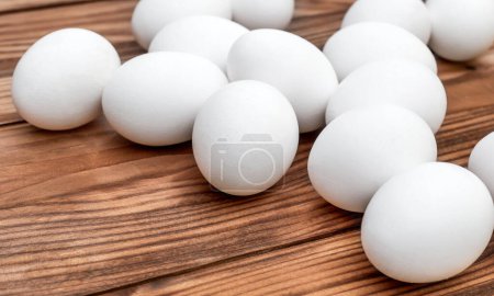 White eggs on the brown wooden table. 