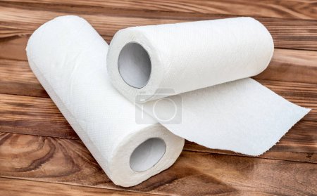 Two paper kitchen towels on the brown wooden table.