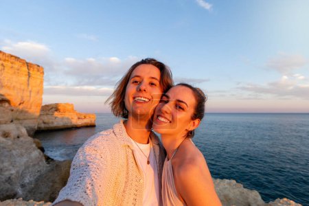 Téléchargez les photos : Faire place à l'amour au coucher du soleil : Gros plan, selfie d'un couple sur une falaise surplombant l'océan au coucher du soleil pendant les vacances d'été. - en image libre de droit