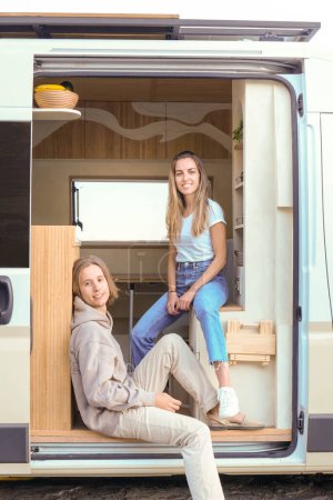 Photo for Two young person enjoy a comfortable ride in the entrance of a luxurious campervan. - Royalty Free Image