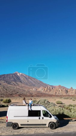 A van is parked on the side of the road in a drone view of the Teide volcano mountain in Tenerife.