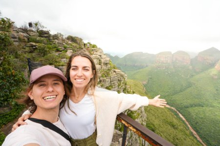 Ein glückliches Paar hält einen Moment zusammen und lächelt für ein Selfie vor der atemberaubenden Kulisse der Drakensberger Berge in Südafrika.