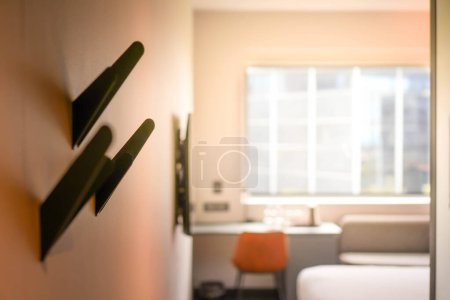 A blurred image capturing the interior of a hotel room featuring a bed and a desk with big window with copy space