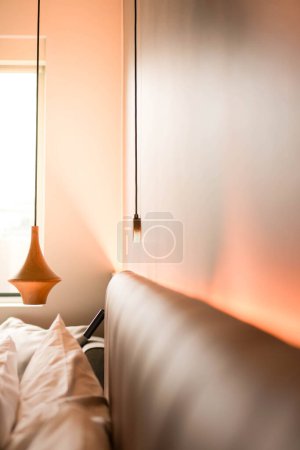 Photo for A hotel room featuring a comfortable bed and an illuminating lamp with copy space - Royalty Free Image