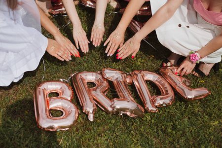 bridal party, bachelorette party, the word BRIDE from golden balls on the grass