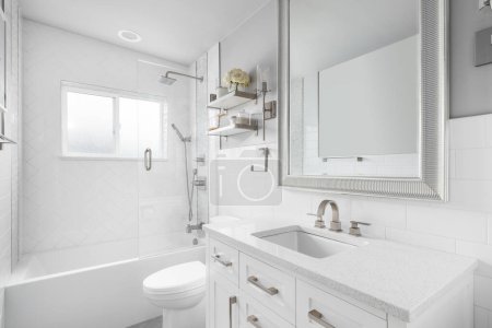 A bathroom with a white vanity cabinet, granite countertop, and a shower lined with large herringbone tiles.