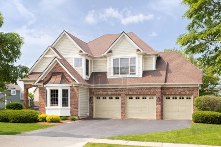 Téléchargez les photos : Naperville, IL, USA - 17 mai 2023 : Une grande maison avec un revêtement en brique rouge et jaune, un garage pour trois voitures et un bel aménagement paysager. - en image libre de droit