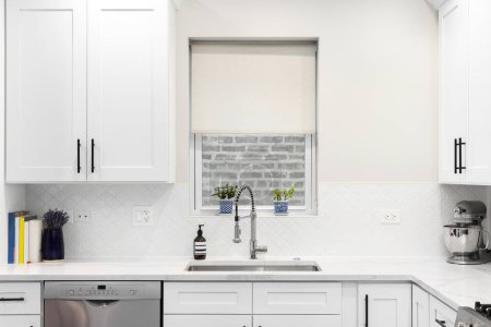 Photo for A white kitchen detail with an arabesque backsplash tile, a stainless steel faucet and sink, and a white marble countertop. - Royalty Free Image