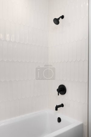 Téléchargez les photos : Une douche et une baignoire avec carrelage en piquet de bronzage et robinet noir et pomme de douche. - en image libre de droit